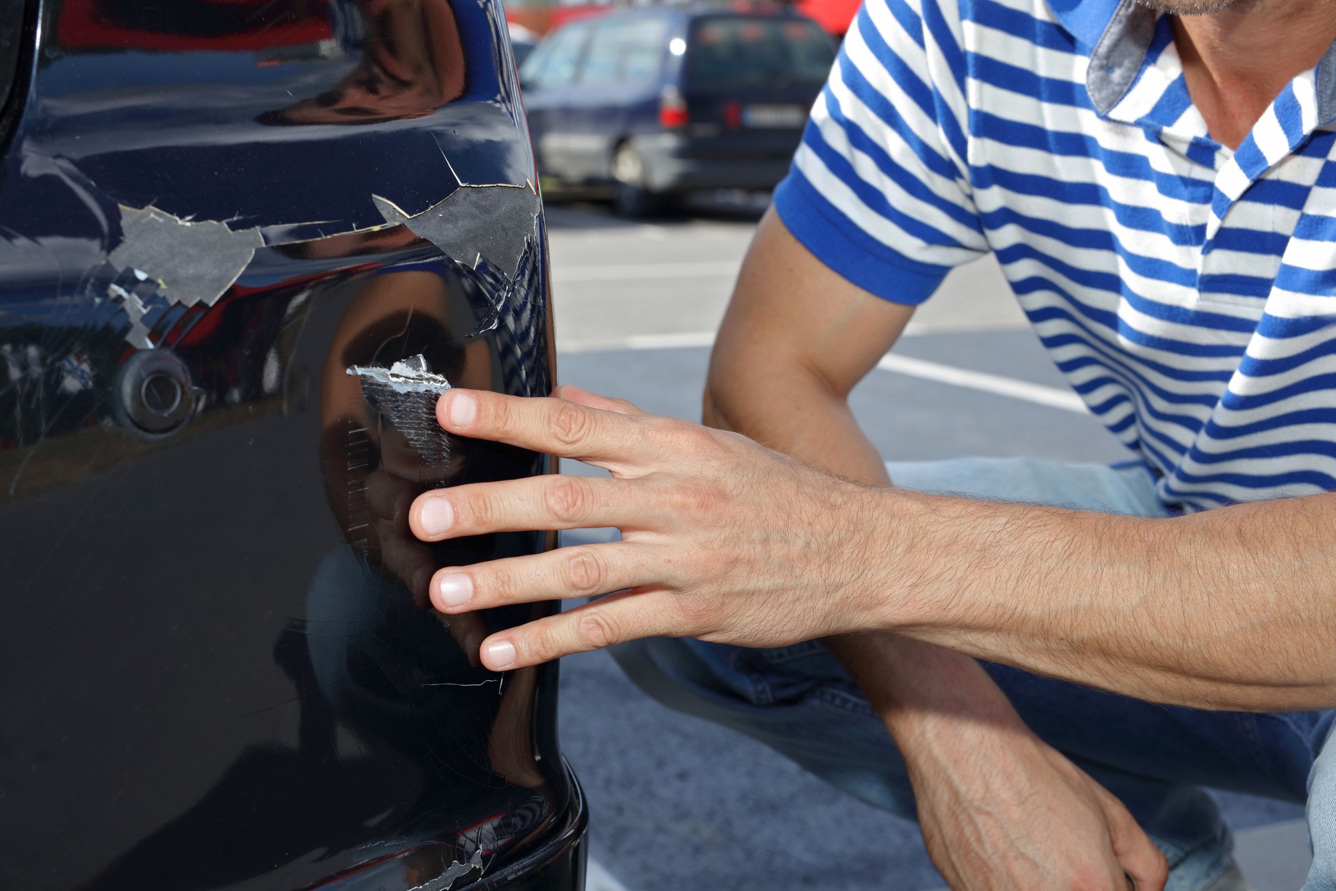 Auto auf Parkplatz beschädigt. Mann überprüft Auto Kratzer und Dellen